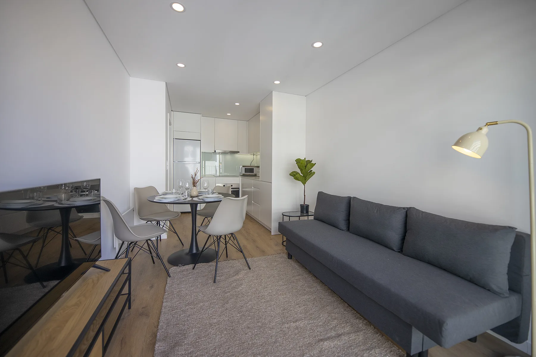 Una luminosa sala de estar y comedor con sofá, mesa y cocina abierta.
