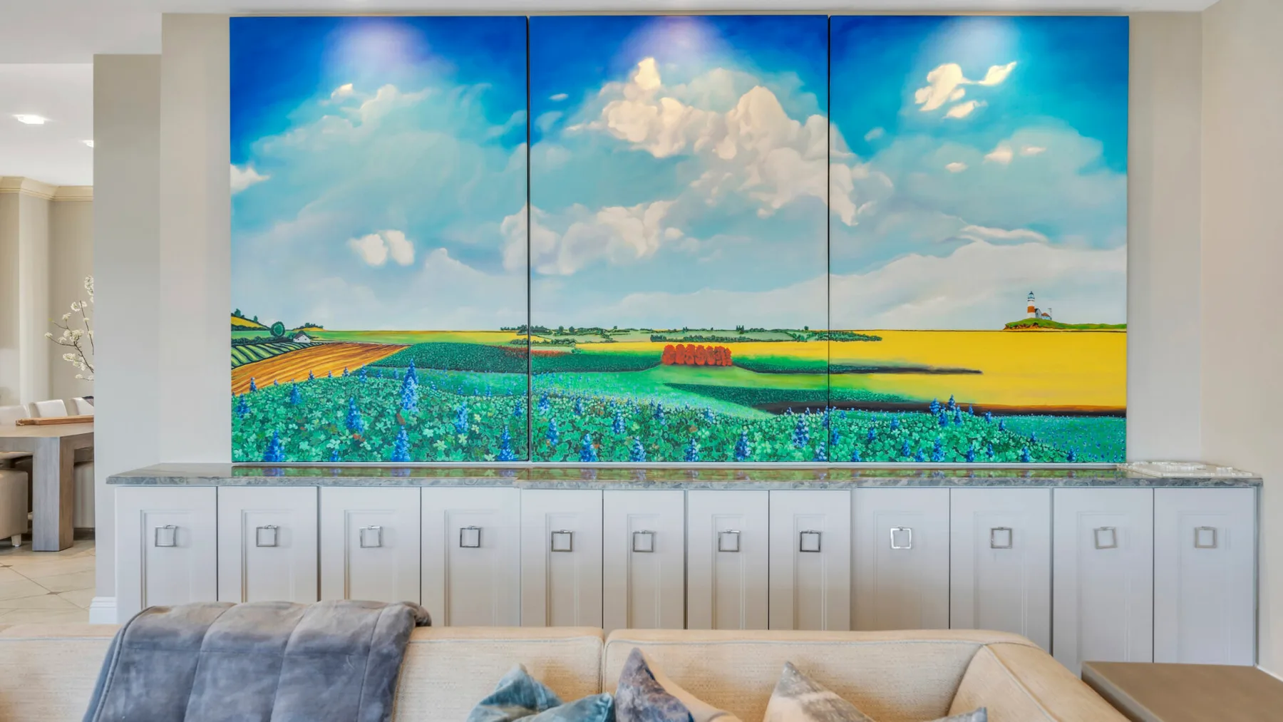 Una sala de estar con asientos bajo un gran mural de paisaje colorido.