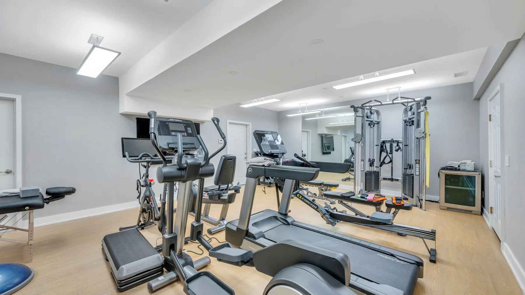 Una sala de entrenamiento con cintas de correr, bicicletas estáticas y equipos de pesas.