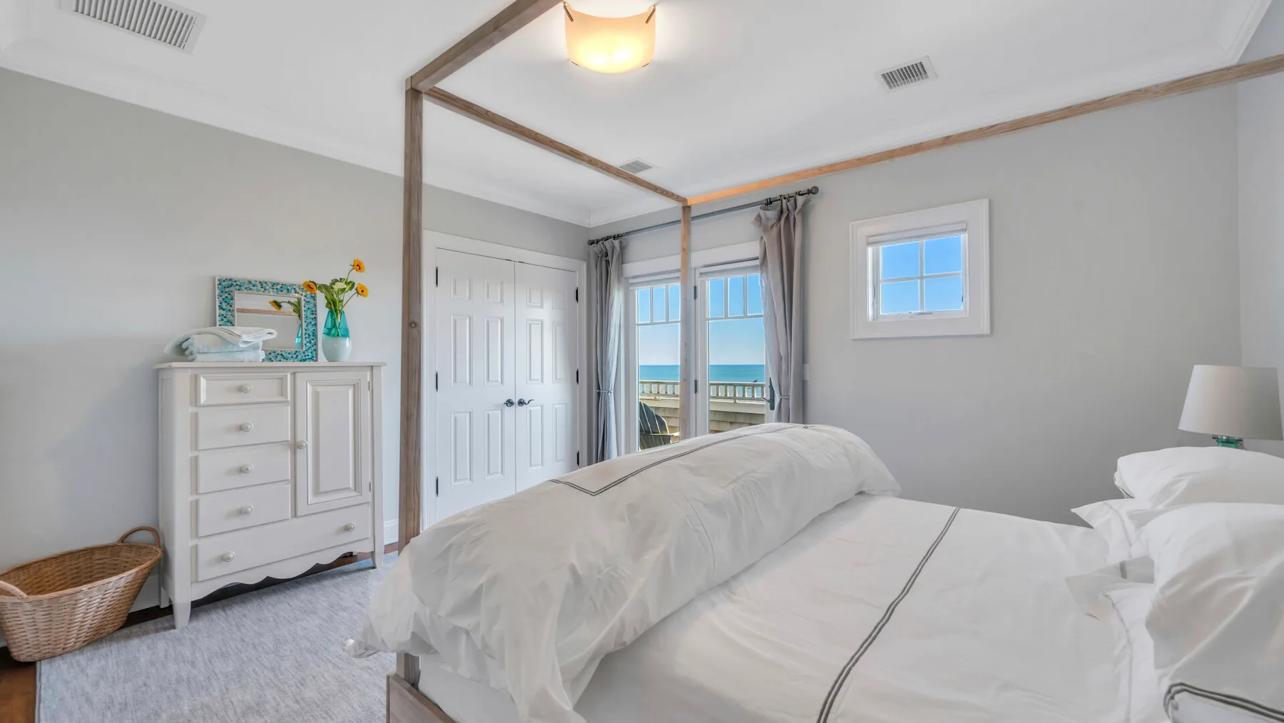 Dormitorio con dos camas, una cómoda y vista al agua a través de las puertas del balcón.