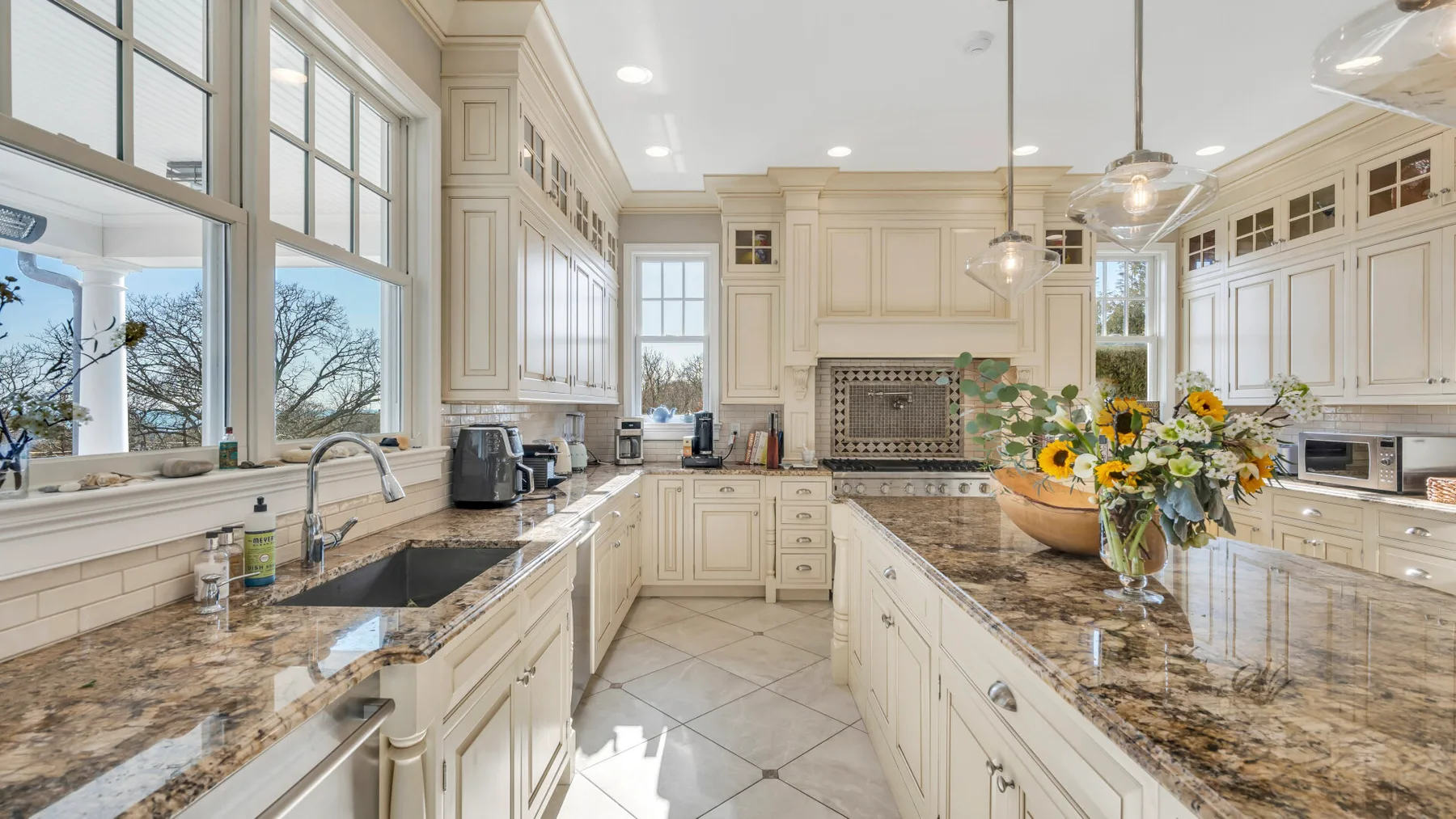 Una cocina luminosa con gabinetes color crema, amplias ventanas y una isla central.