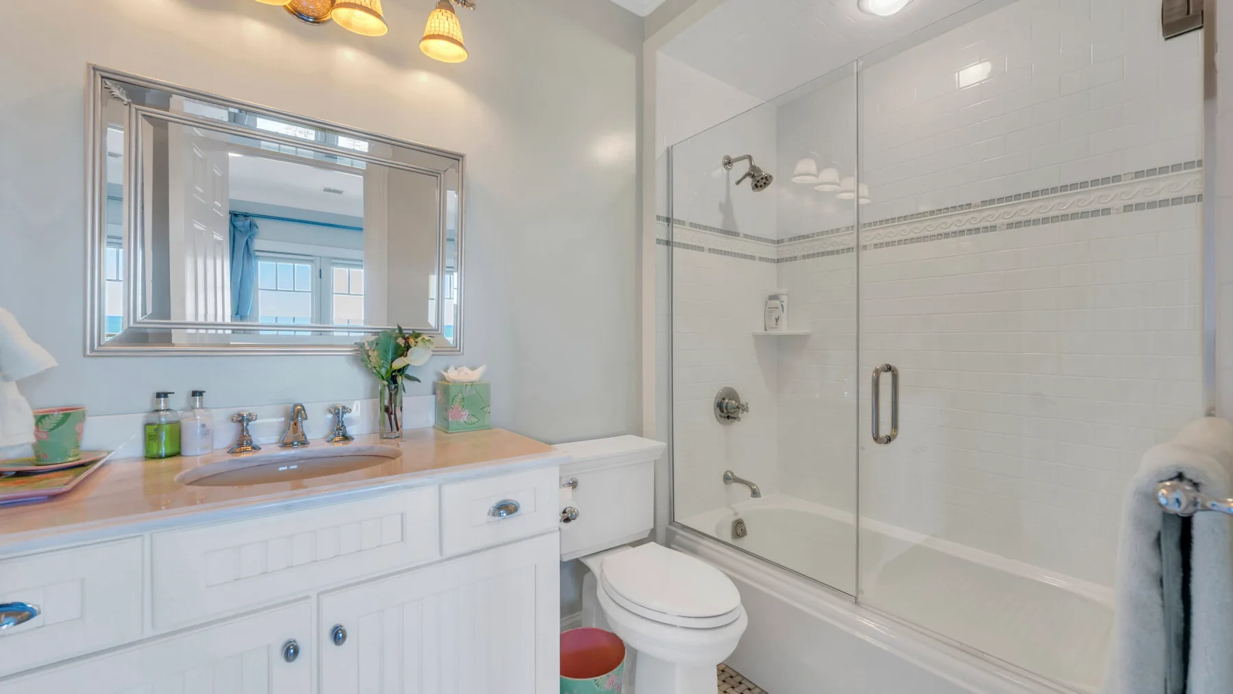 Un baño luminoso con lavabo y bañera con mampara de vidrio.