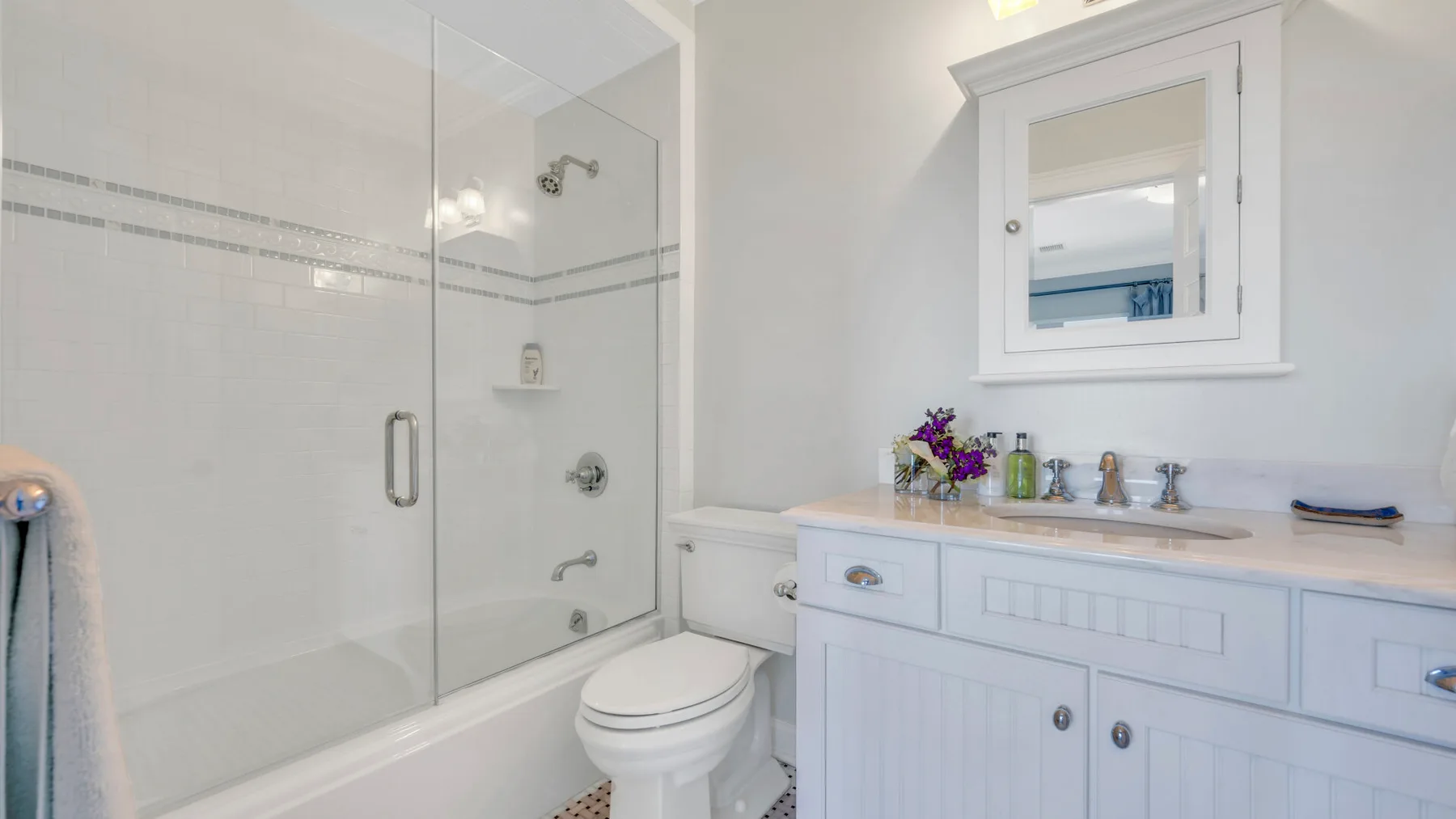 Un baño luminoso con ducha de vidrio, inodoro y tocador blanco.