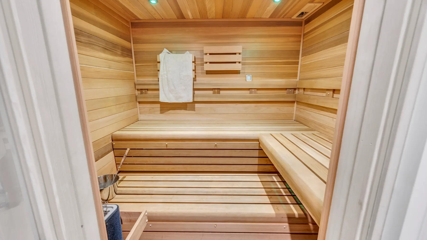 Una sauna revestida de madera con asientos escalonados y una toalla doblada.