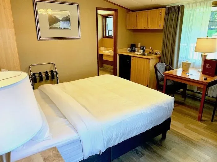 Cabin-style room with bed, desk and small kitchenette.