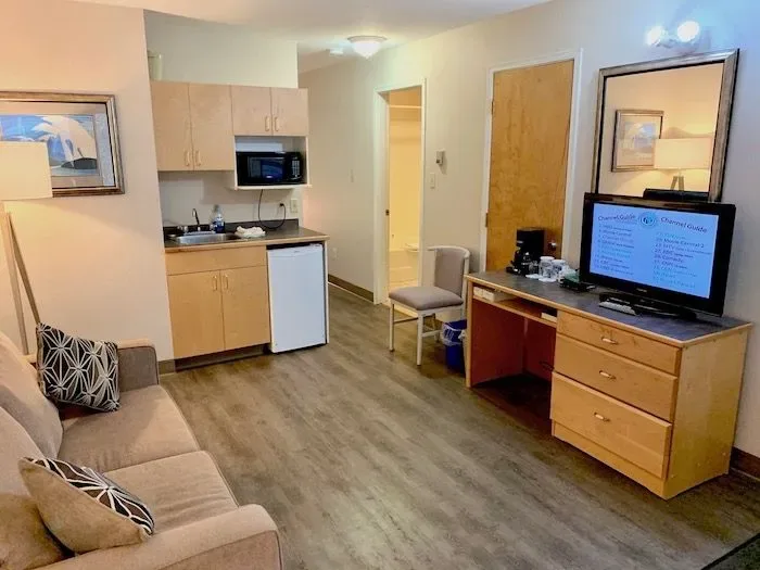 Room 27 with sofa, kitchenette, desk and TV.