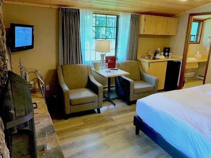 Guest room seating area with armchairs, a table and bed.