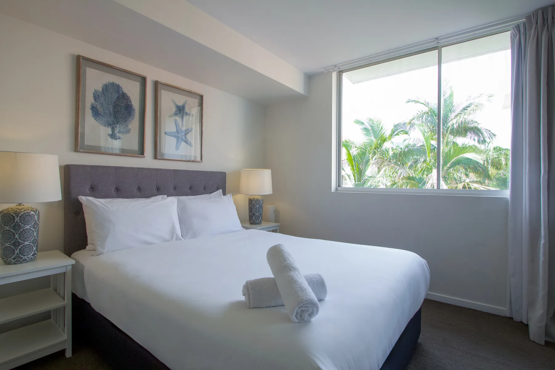 A bedroom with a neatly made bed beside a large window.