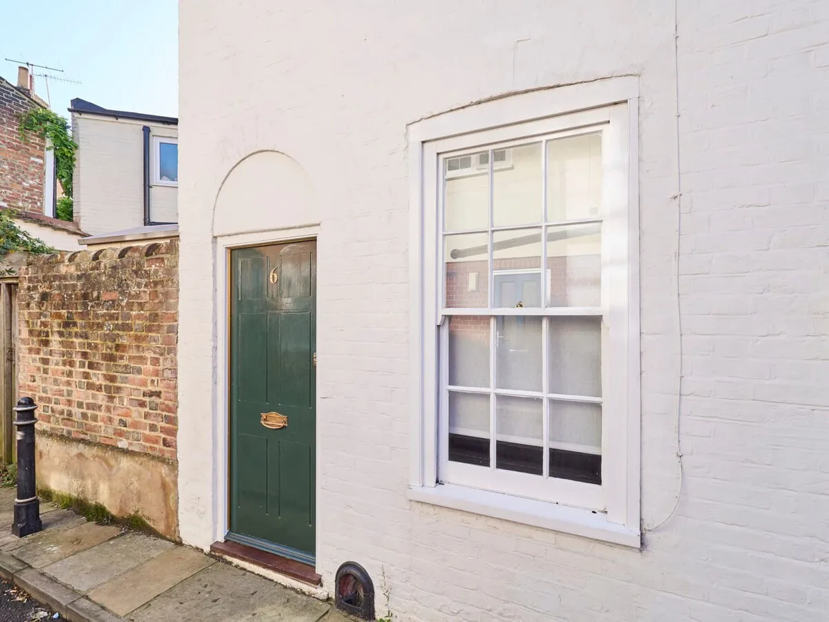 A white brick exterior with a dark green door and a large window.