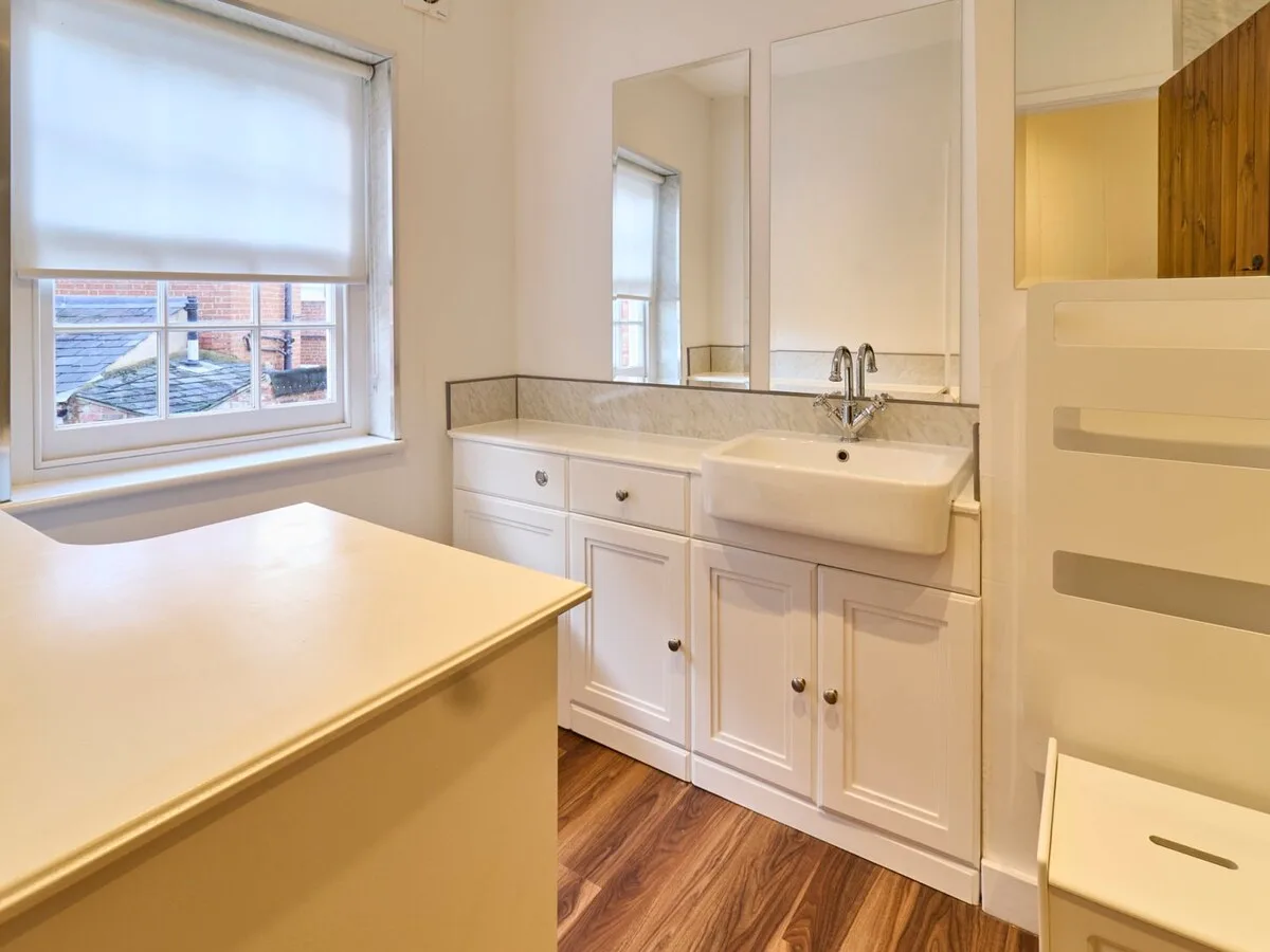 A bright bathroom vanity area with a sink, countertop, and window.