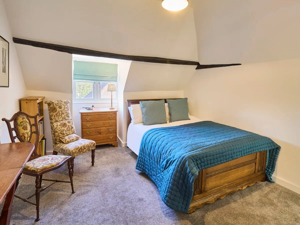 A bedroom with a wooden bed, blue bedding, and a small window.