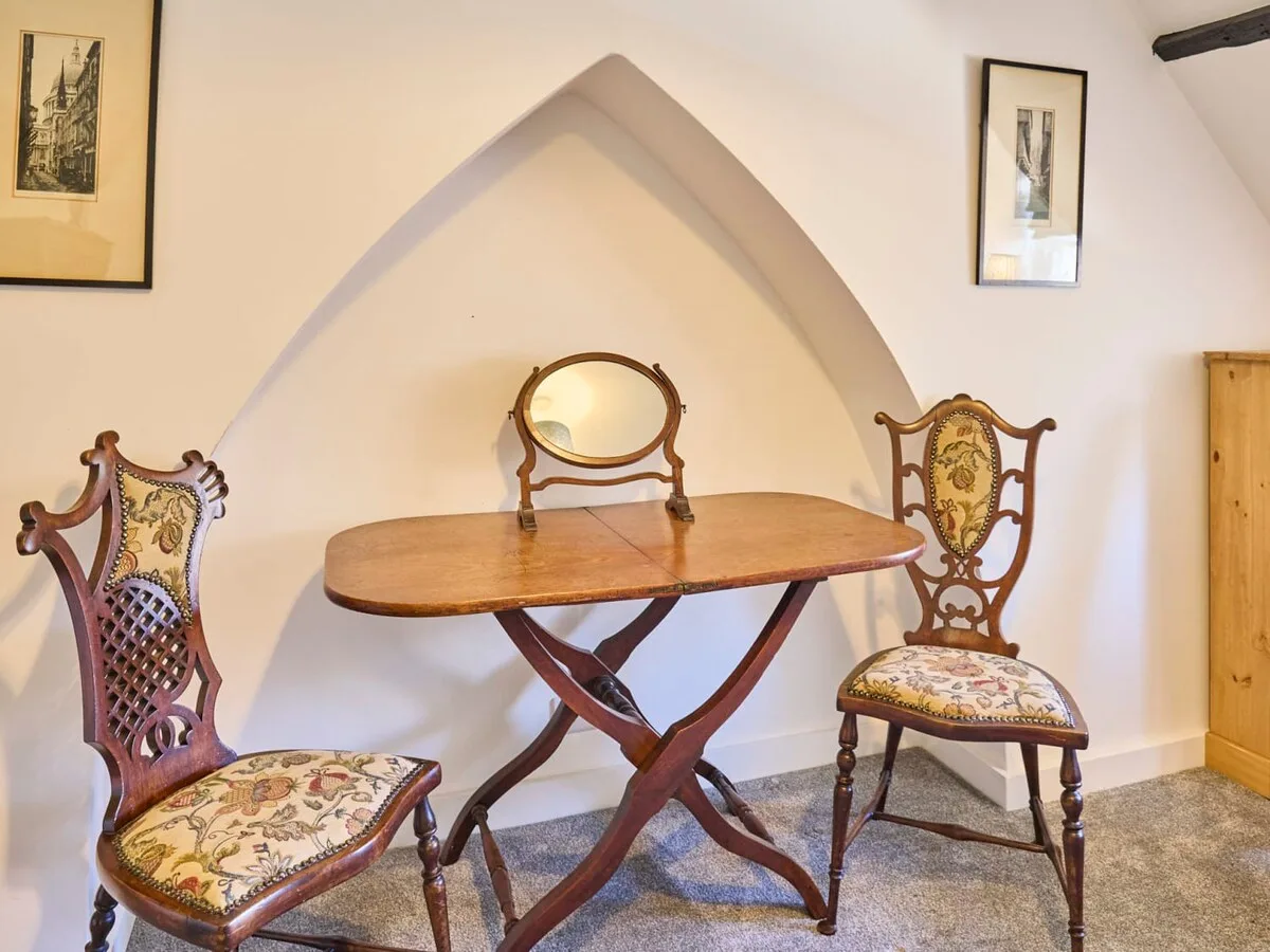 A dining nook with a wooden table, chairs, and a small wall mirror.