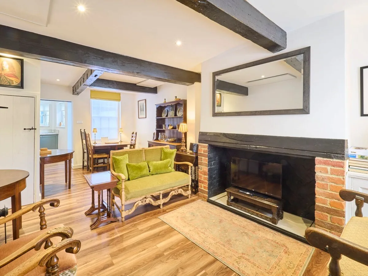 Una sala de estar con asientos verdes, una chimenea y un comedor al fondo.