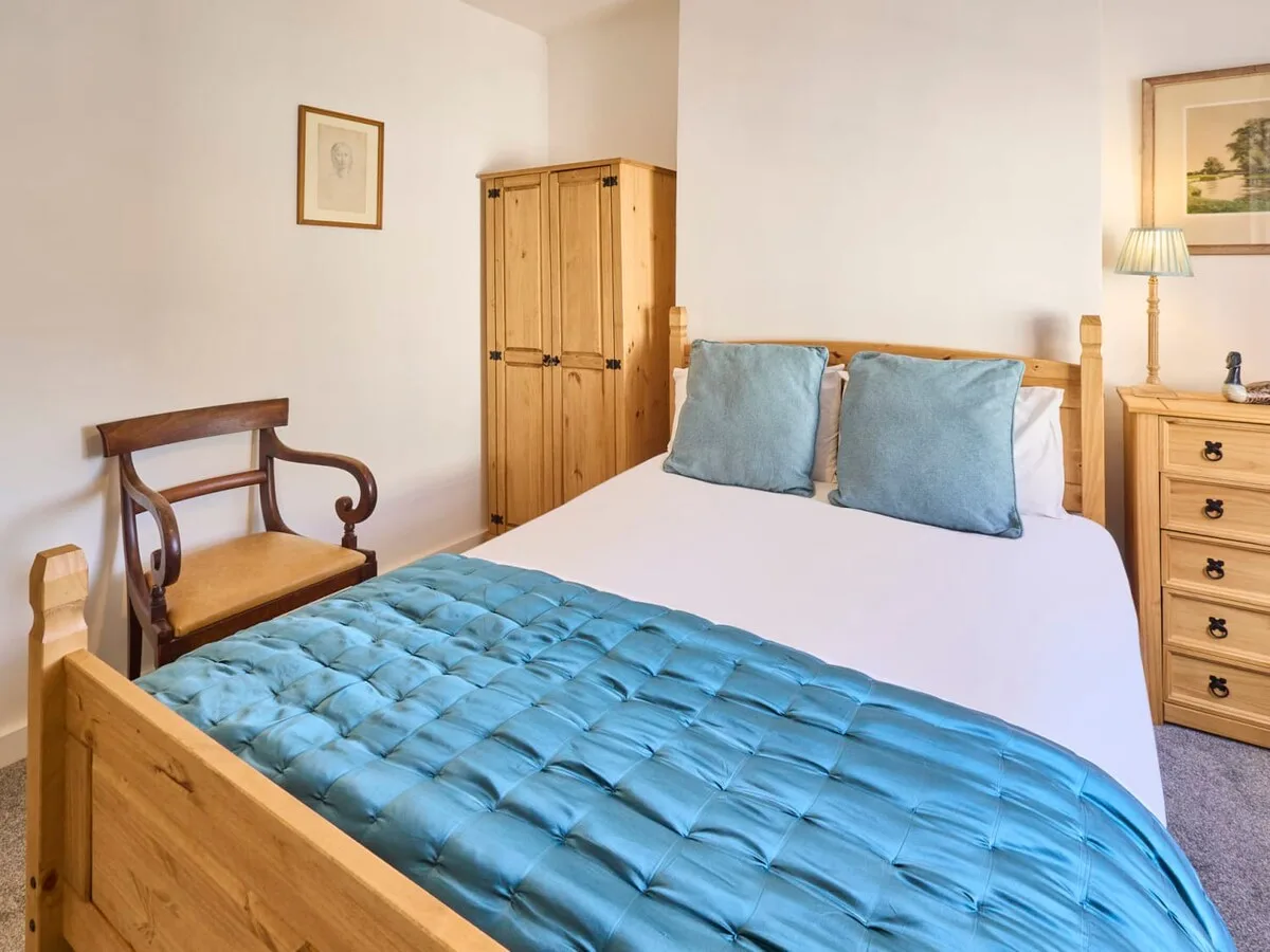A bedroom with a wooden bed, blue bedding, and a wardrobe.