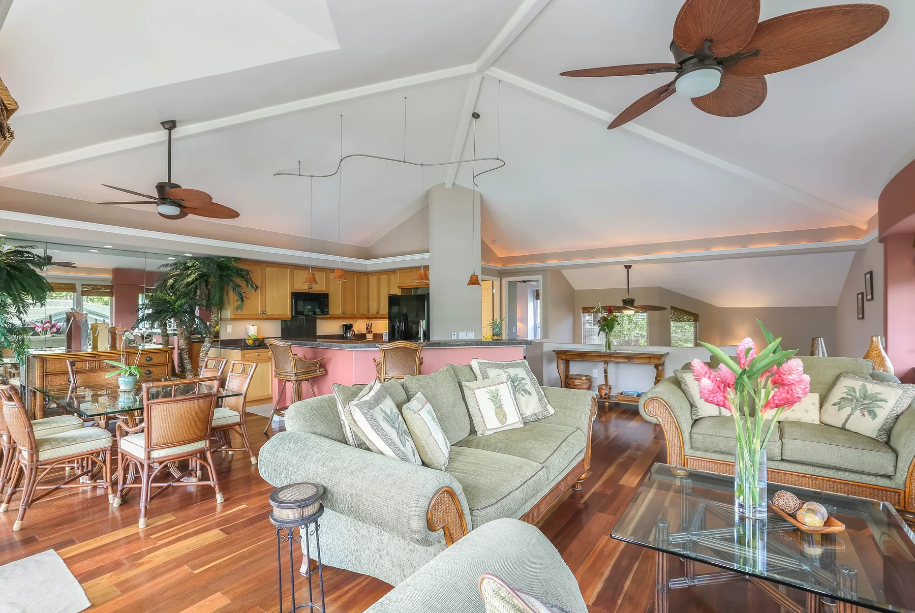 An open living and dining area features seating, a glass coffee table, and a kitchen beyond.