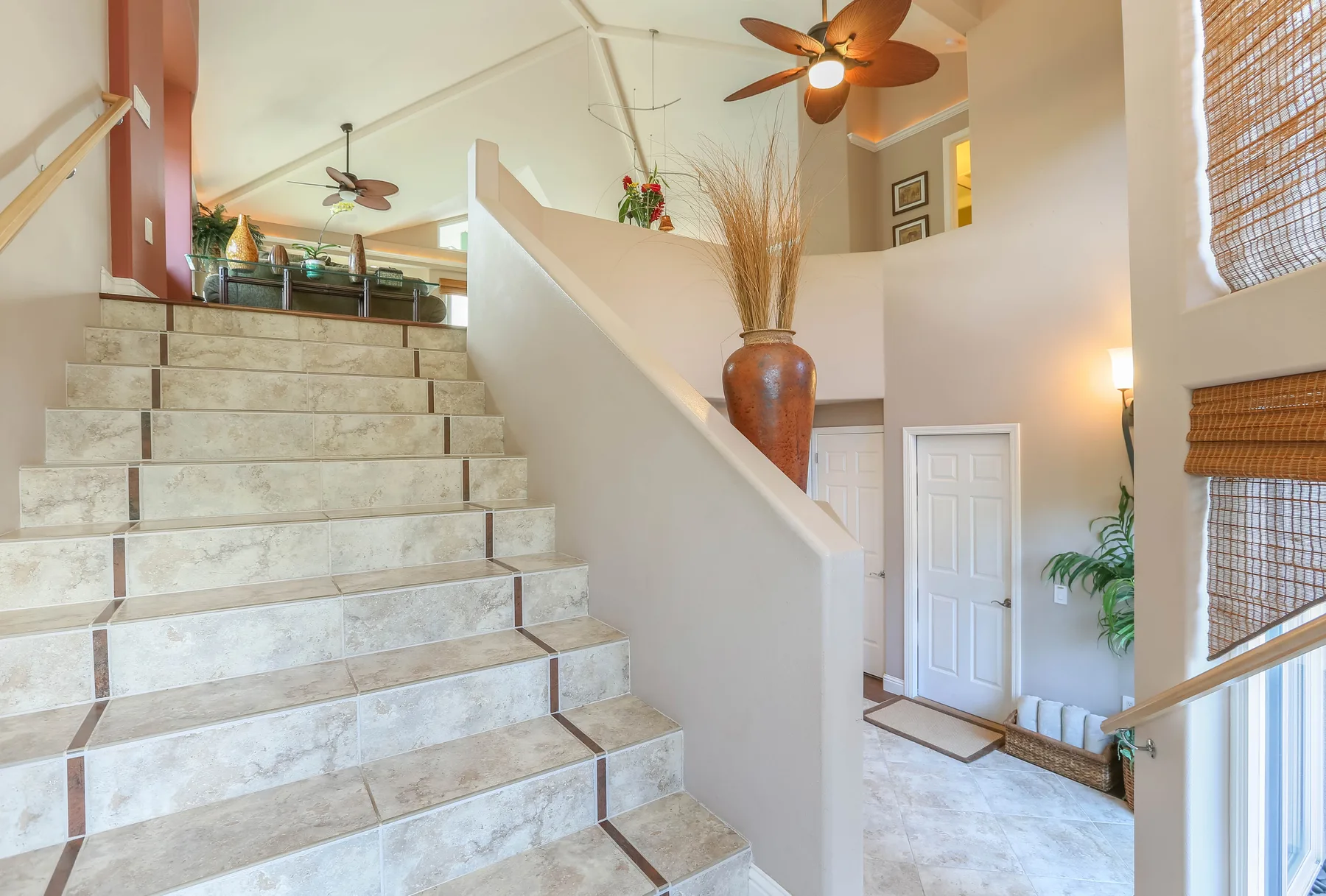A bright interior foyer with a broad staircase and a white entry door.