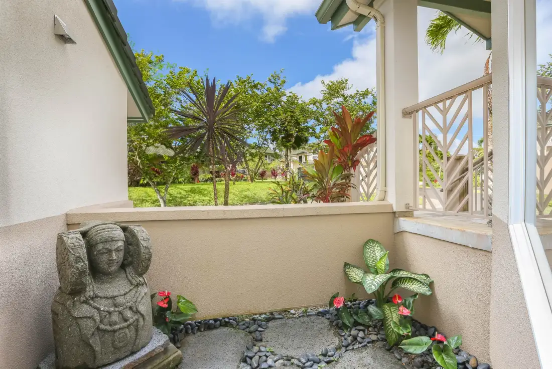 A small outdoor patio with a stone statue and plants.