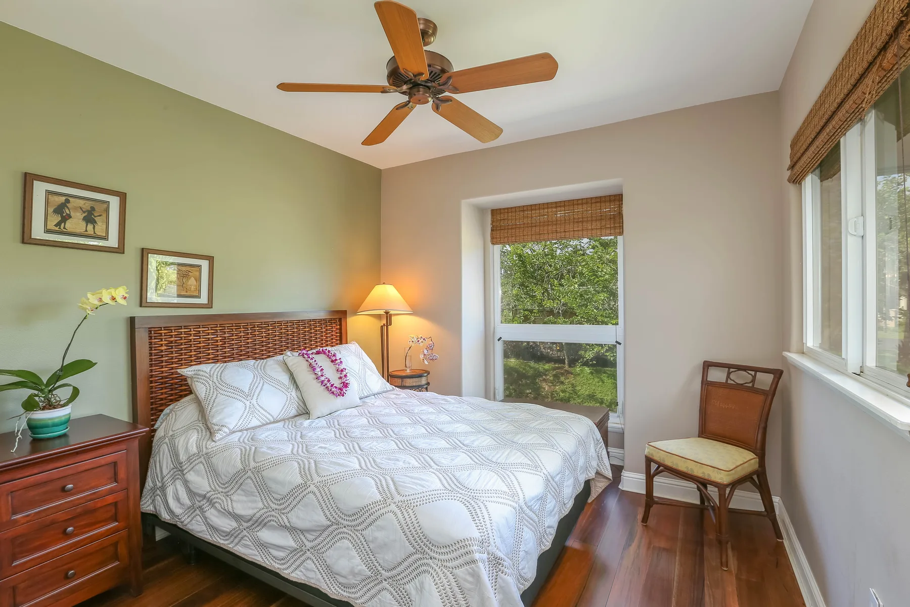 A bedroom with a bed, bedside table, and windows overlooking greenery.