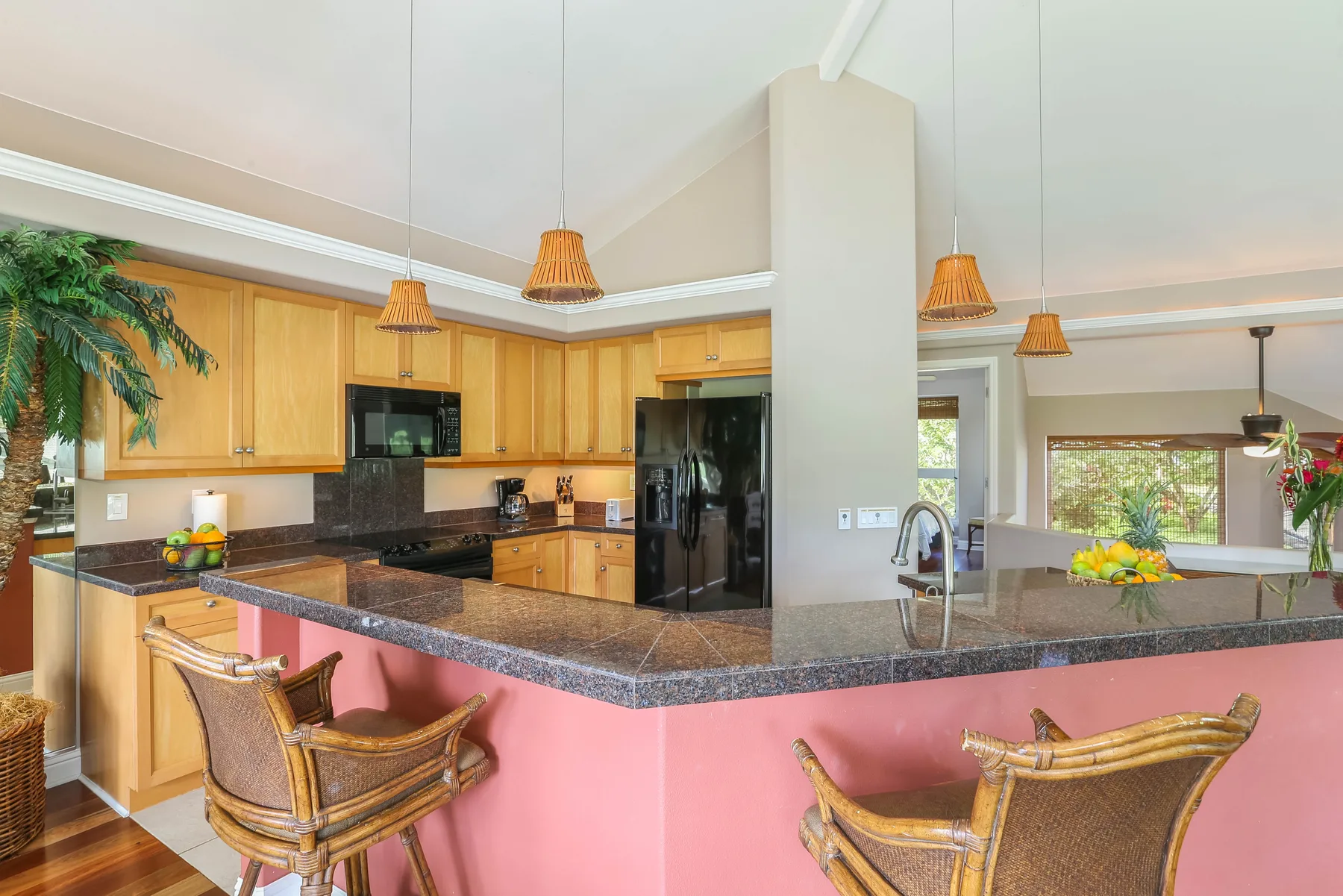 An open kitchen with wooden cabinets and a large counter with bar seating.