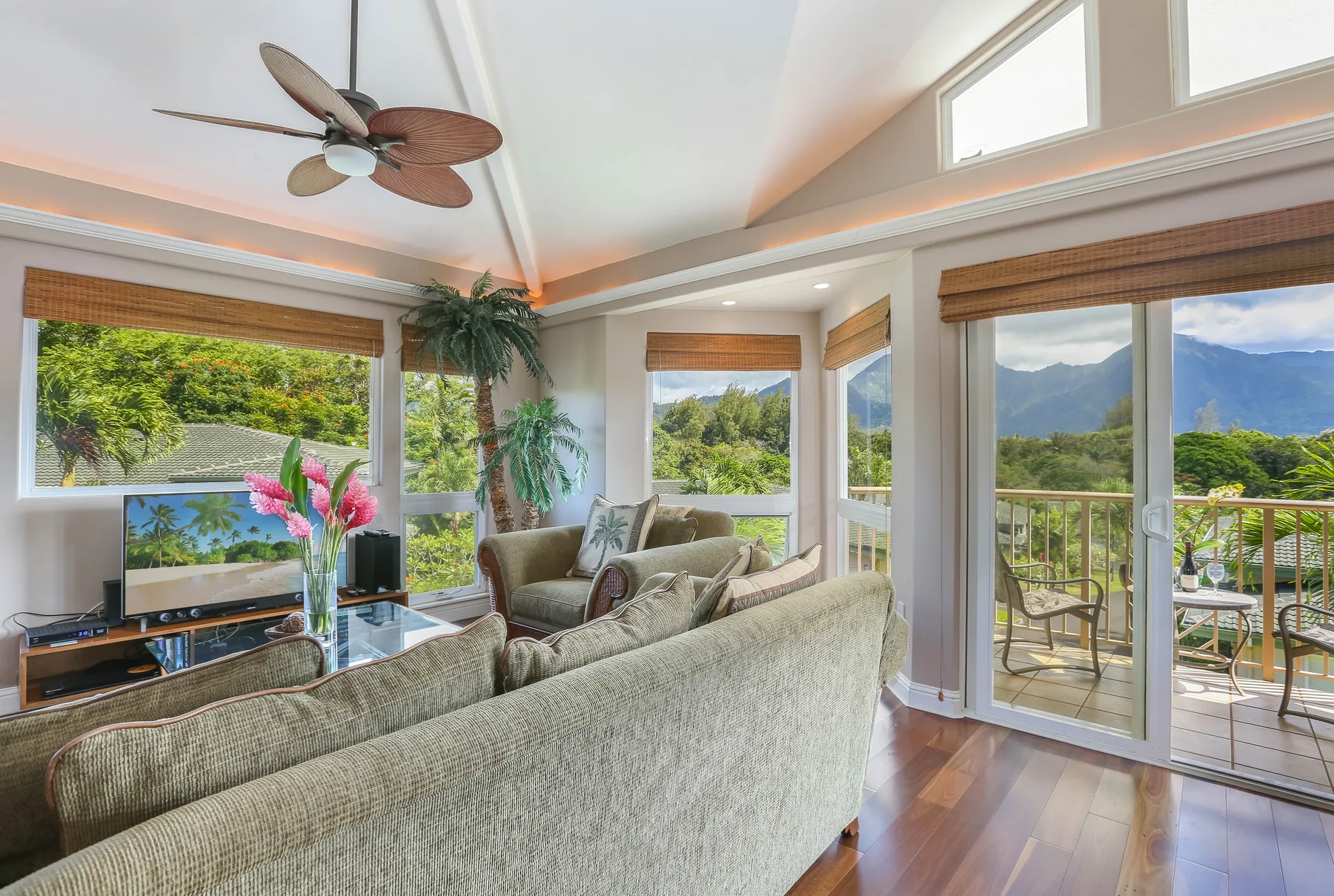 A bright living room with seating beside large windows overlooking green hills.