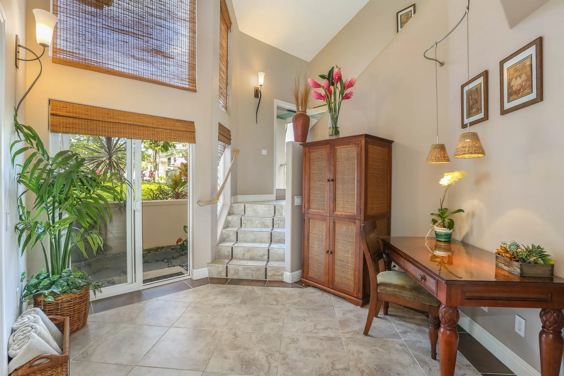 A bright entryway with a tiled staircase, wooden cabinet, and desk.
