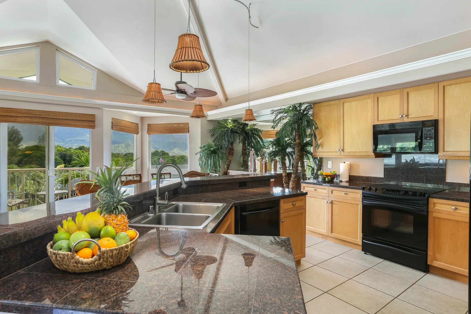 Una cocina luminosa con una isla grande, gabinetes de madera y ventanas con vista a la vegetación.