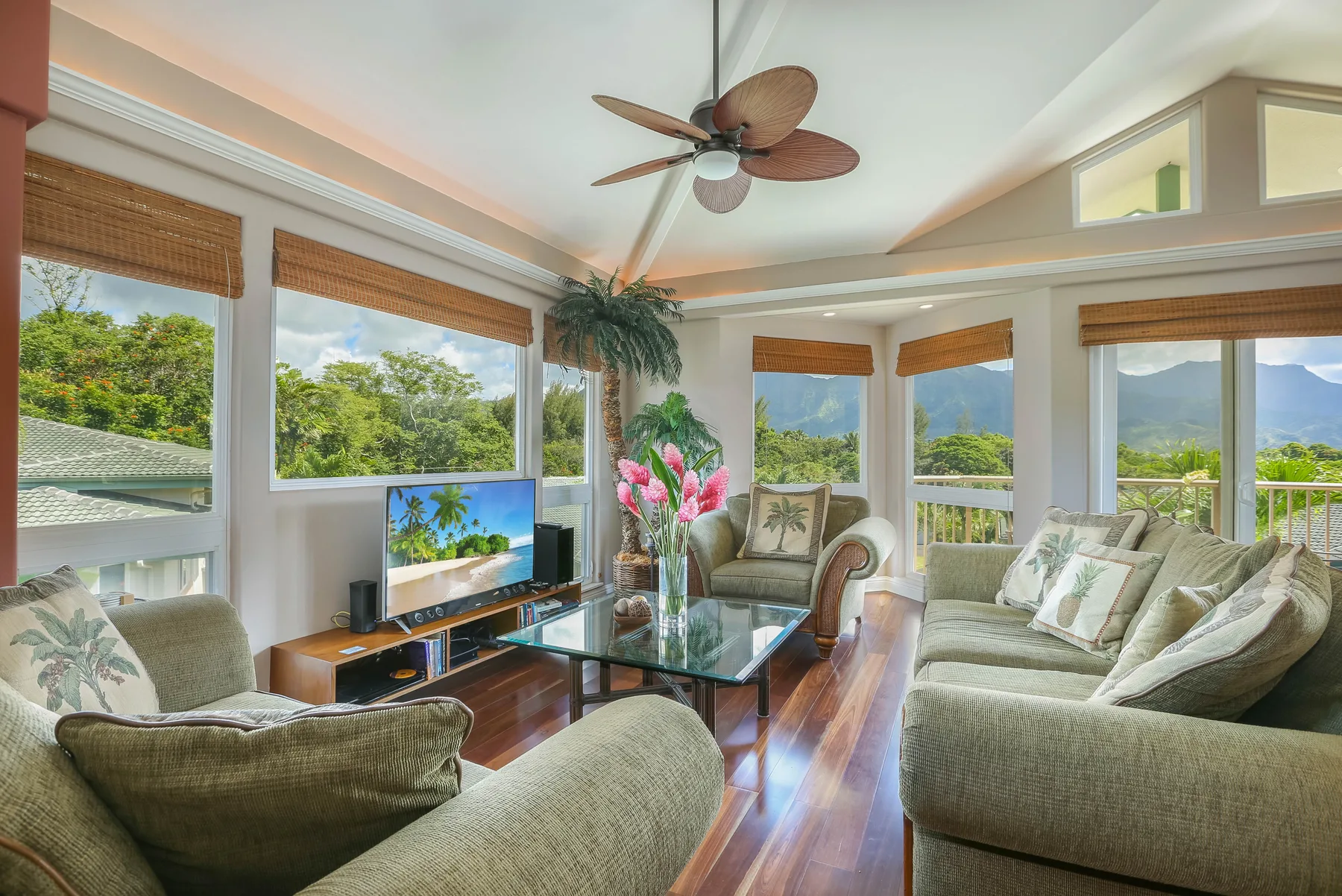 A bright living room with seating, large windows, and a glass coffee table.