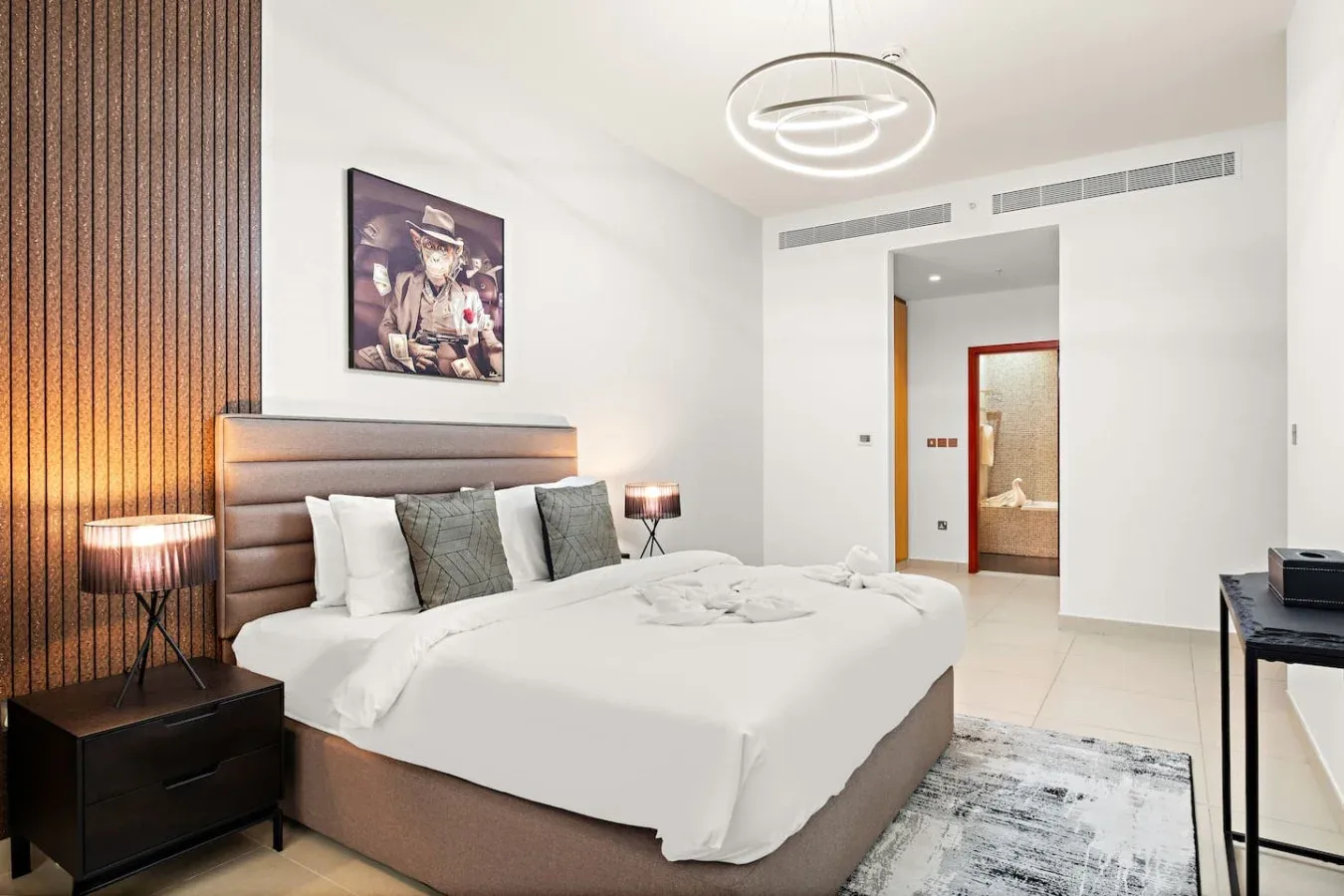 Un dormitorio con una cama bien tendida y una puerta hacia el baño.