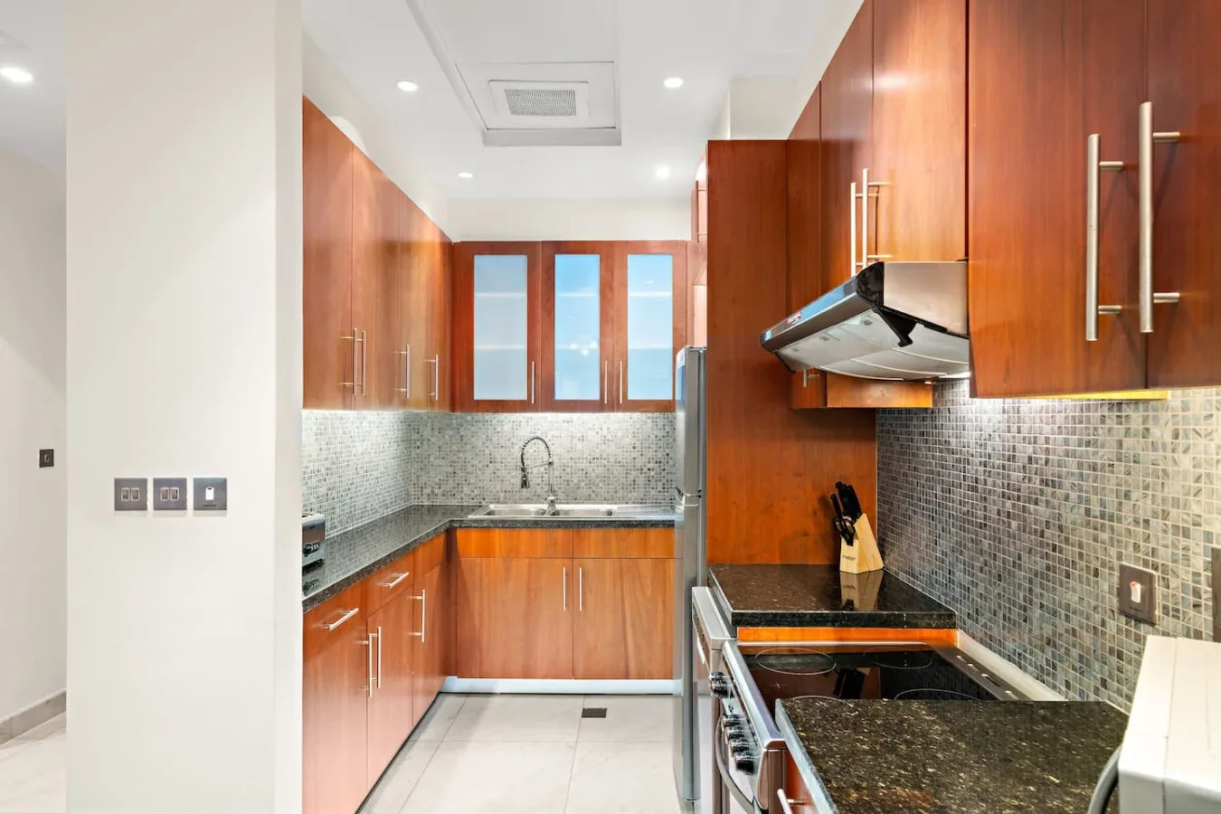 Una cocina moderna con gabinetes de madera, encimeras oscuras y un salpicadero de azulejos.