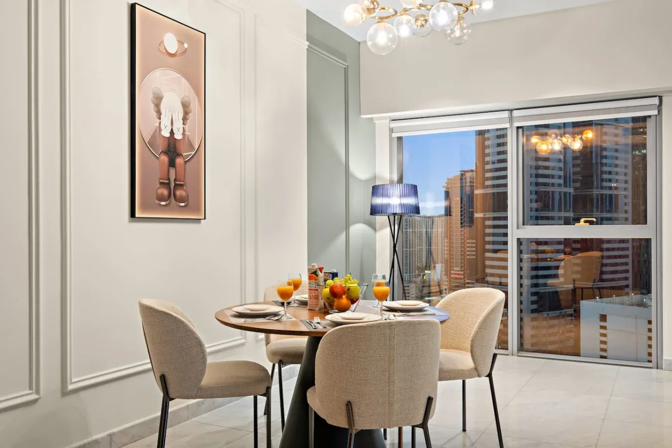 Un comedor con una mesa preparada junto a grandes ventanas con edificios a la vista.
