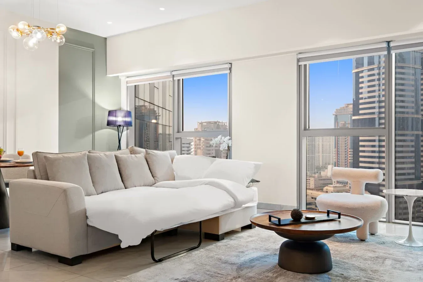 Una sala luminosa con asientos claros y grandes ventanas con vistas a edificios de la ciudad.