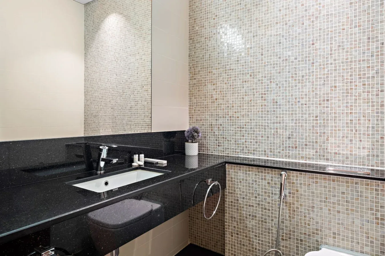 Un baño con azulejos, un mueble oscuro, lavabo y espejo.