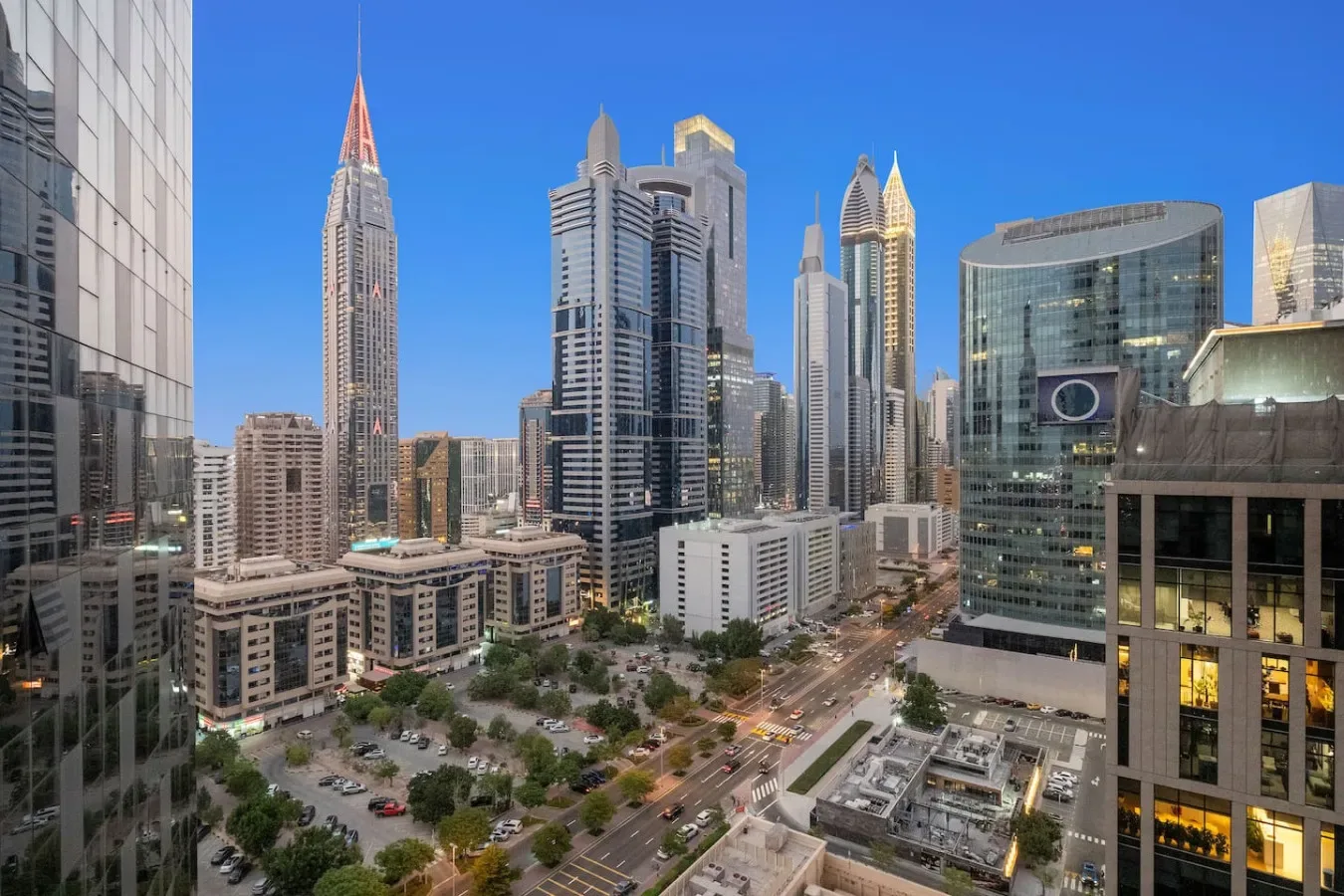 Un horizonte urbano de modernos edificios altos se alza sobre calles y zonas ajardinadas.