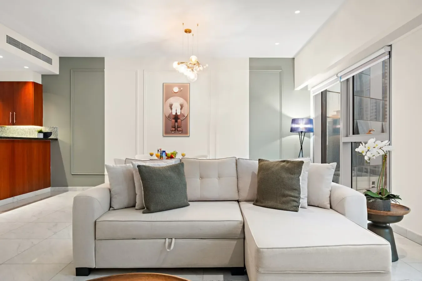 Una sala luminosa con un sofá seccional y grandes ventanas.