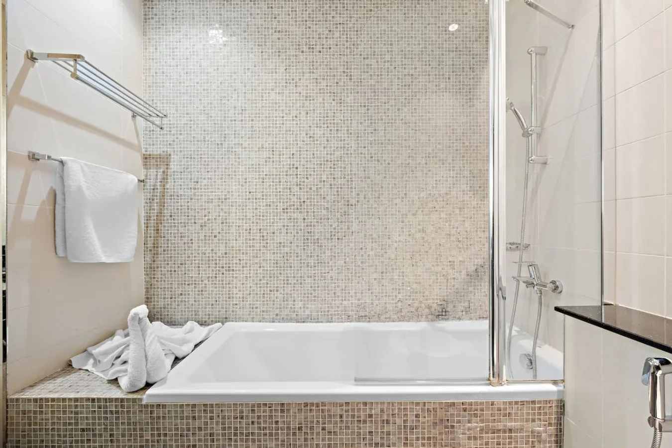 Un baño alicatado con bañera, ducha y toallero.