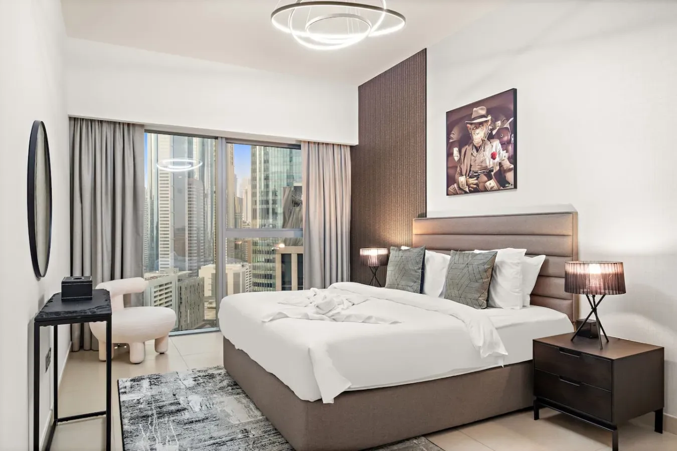 Un dormitorio luminoso con una cama grande junto a una ventana con vistas a edificios de la ciudad.
