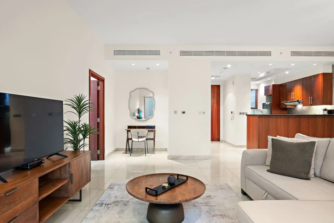 Una sala luminosa con sofá, televisor y una cocina abierta.