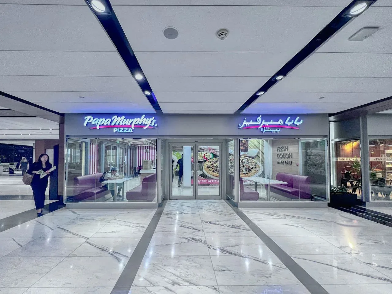 La fachada de una pizzería da a un luminoso pasillo interior de un centro comercial.