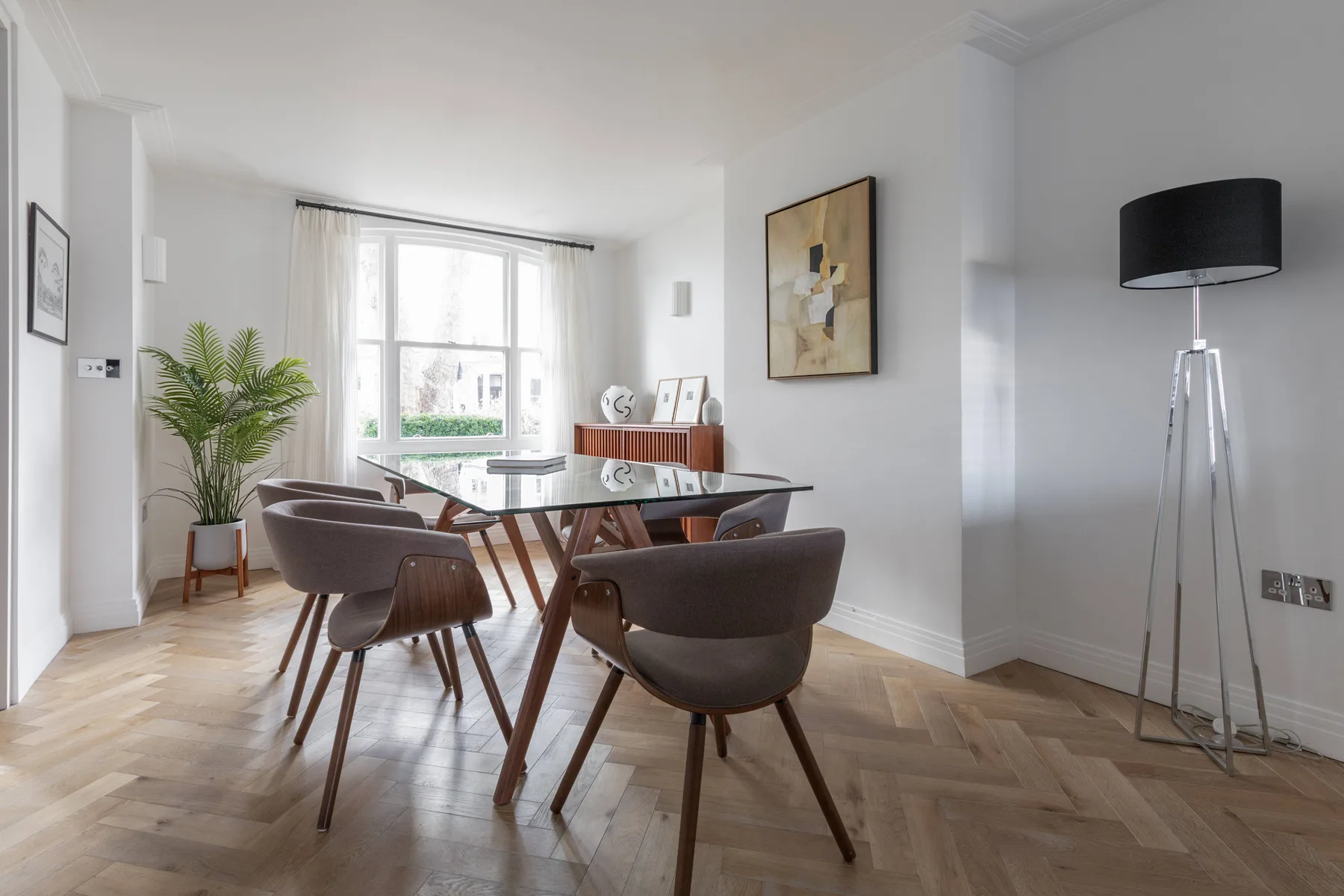 A bright dining area with a glass table and upholstered seating.