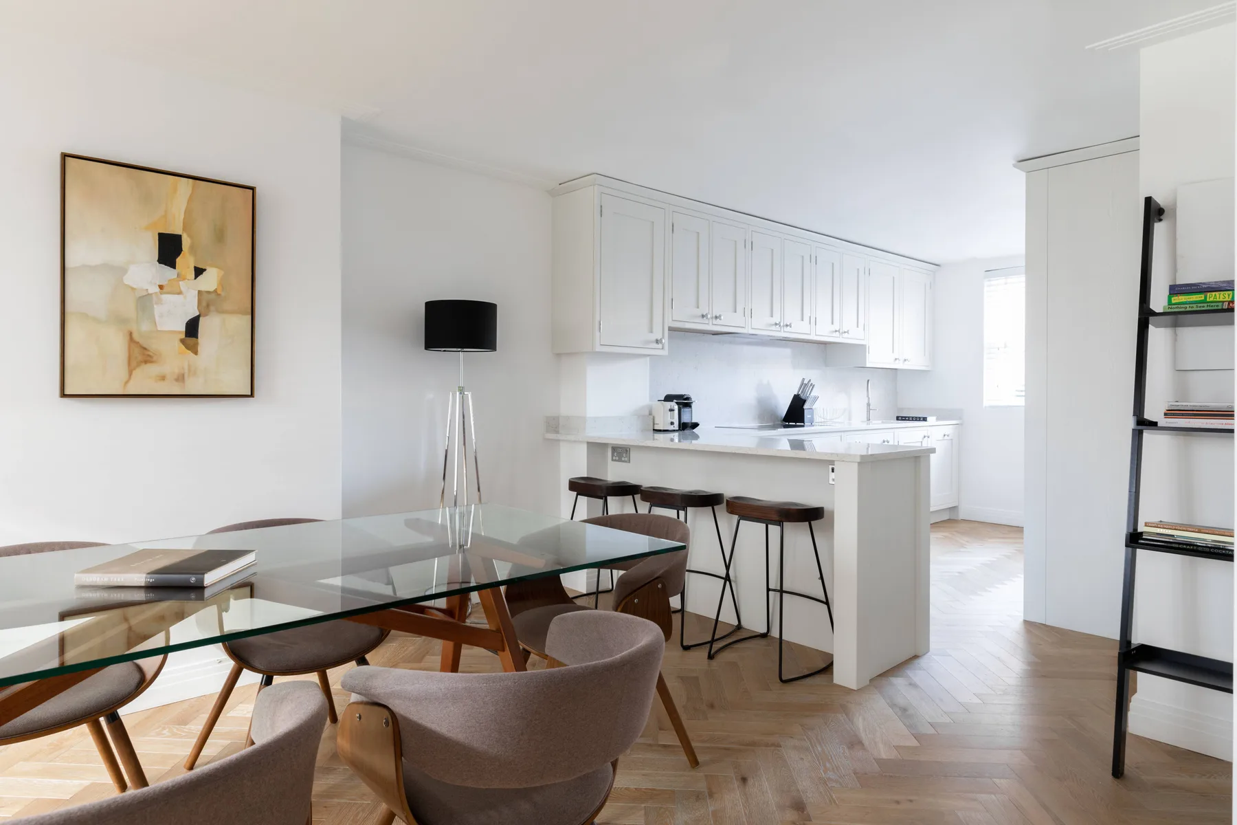An open-plan dining and kitchen area with a glass dining table and counter seating.