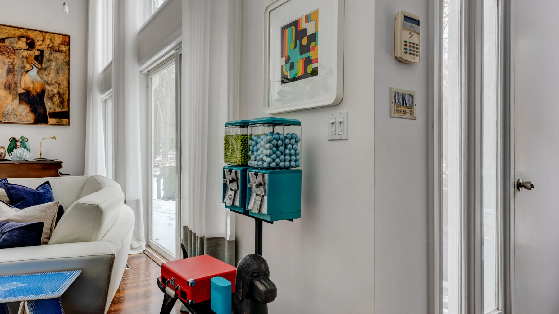 A bright living room with seating, tall windows, and colorful wall art.