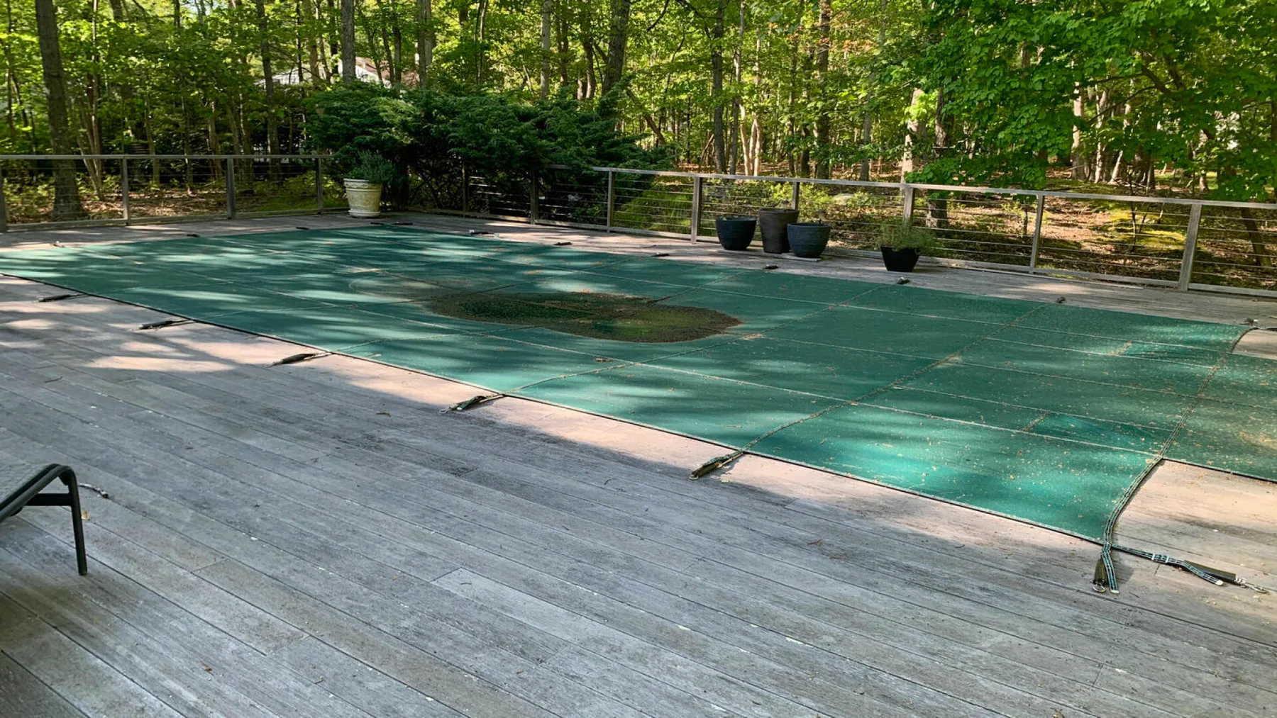 A wooded outdoor pool area with a broad deck and surrounding trees.