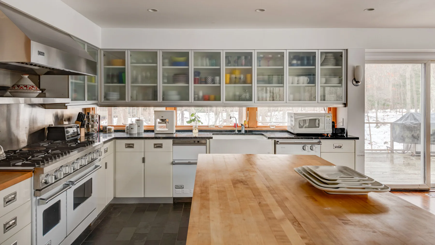 A modern kitchen with glass-front cabinets and a large wooden island.