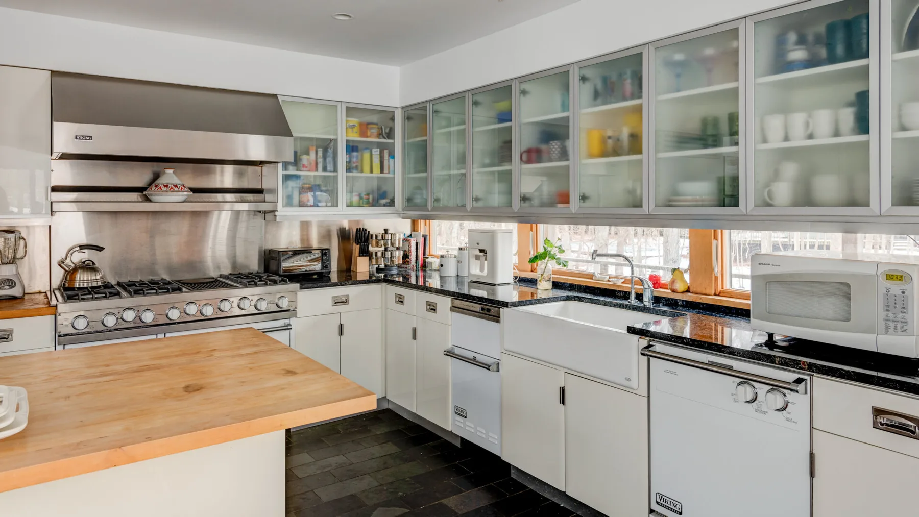 A spacious kitchen with white cabinets, a large range, and a wooden island.