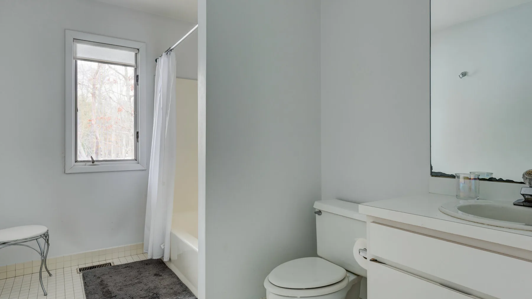 A bathroom with a bathtub, shower curtain, toilet, and sink.
