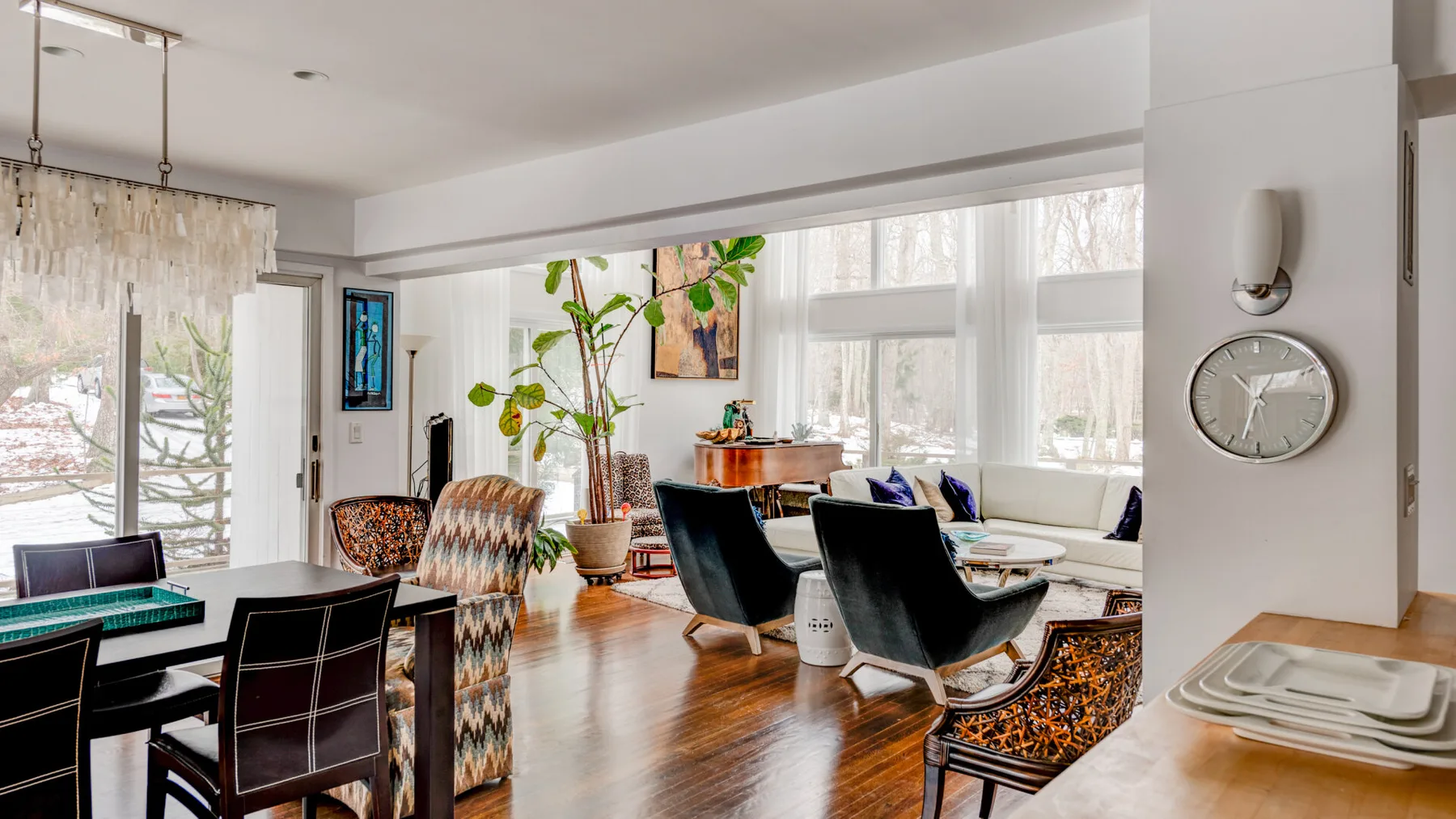 A bright living and dining area with seating, a table, and large windows.