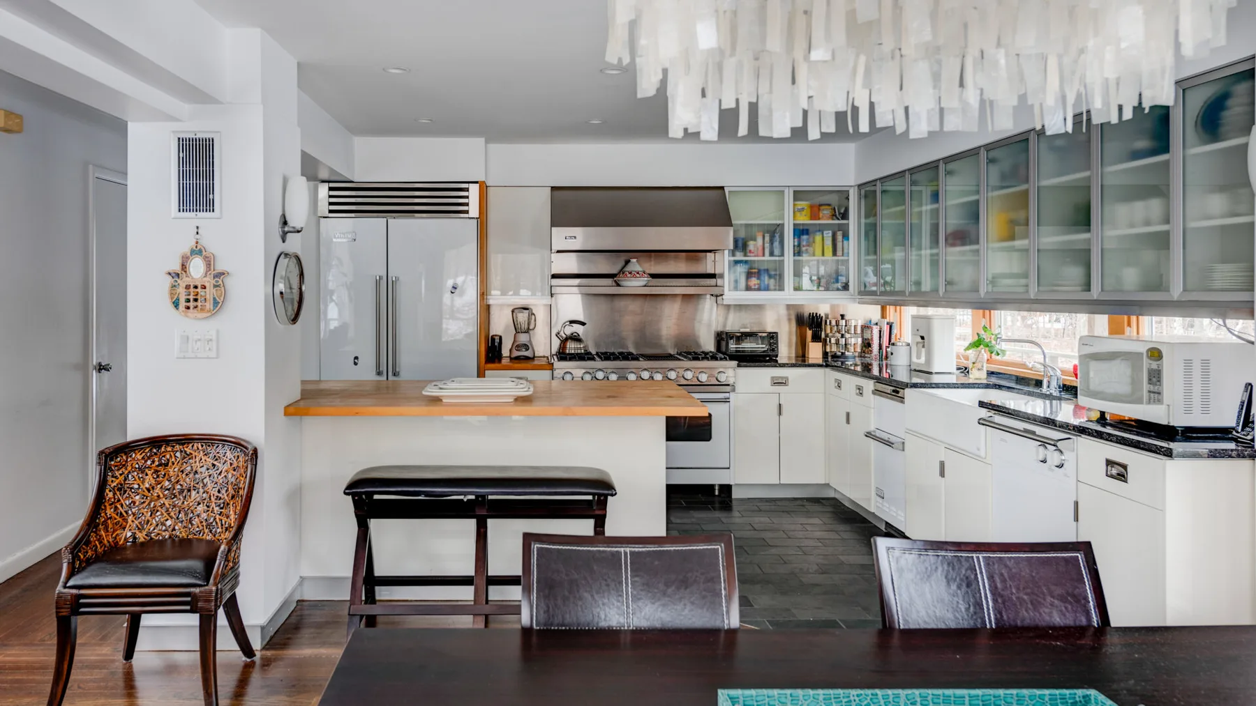 A modern kitchen with white cabinets, a central island, and a dining table.