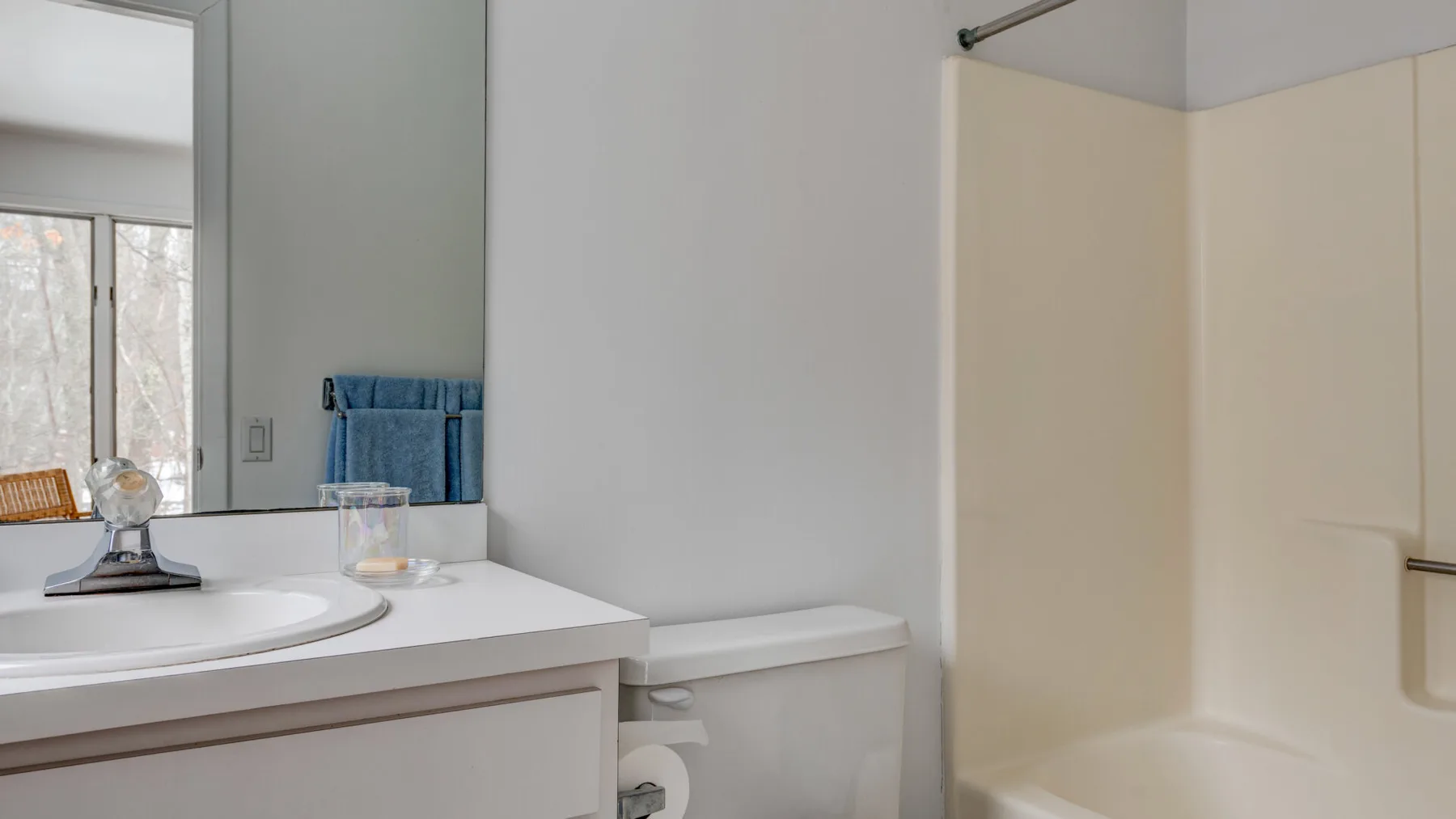 A bathroom vanity and toilet sit beside a shower with a pale curtain.
