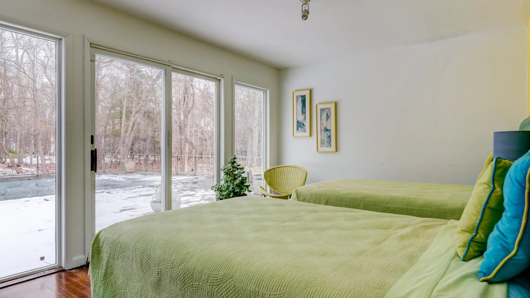 A bedroom with a large bed beside windows overlooking a snowy yard.