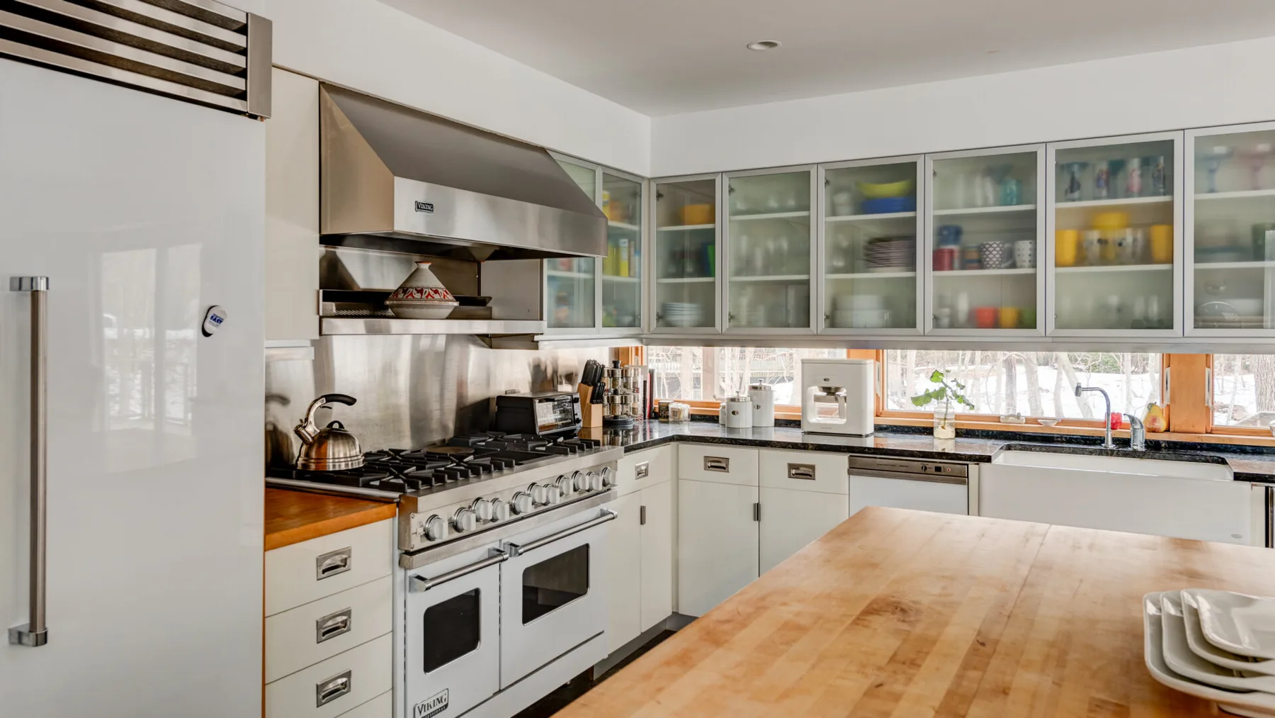 A bright kitchen with white cabinets, a cooking range, and a wooden island.